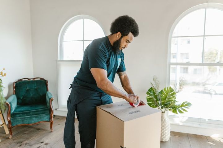 A mover packing and taping a moving box during move preparation