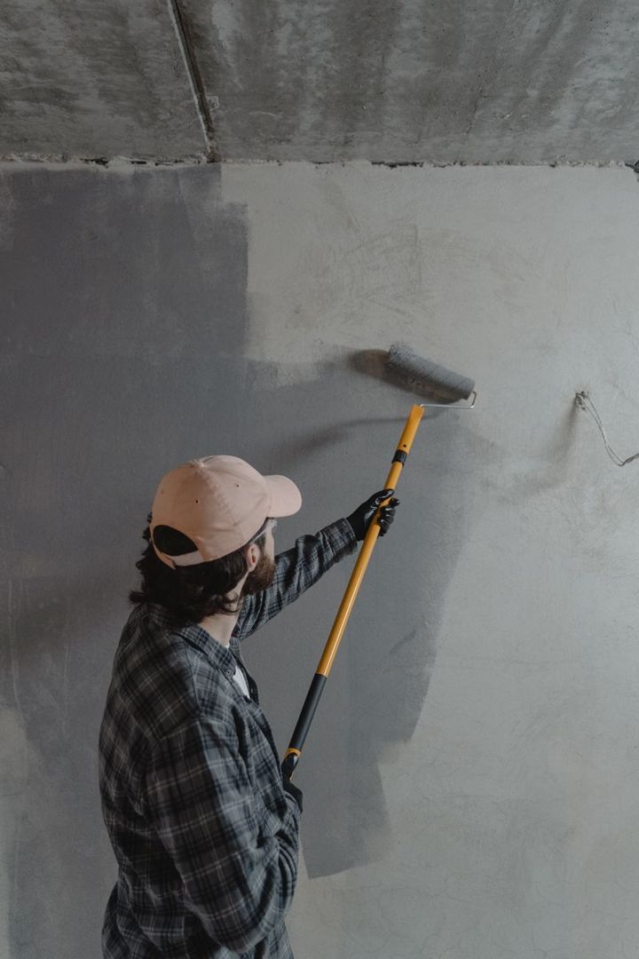 A painter rolling a fresh coat on a wall inside a vacant rental unit during a turnover